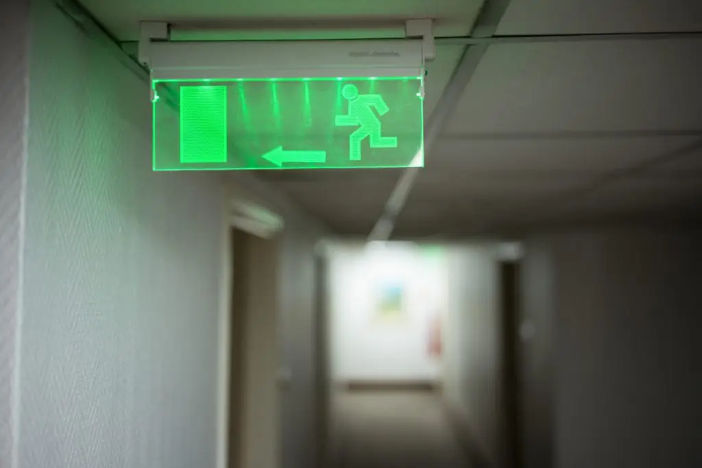 Verlichte nooduitgang boven een deur in een gang